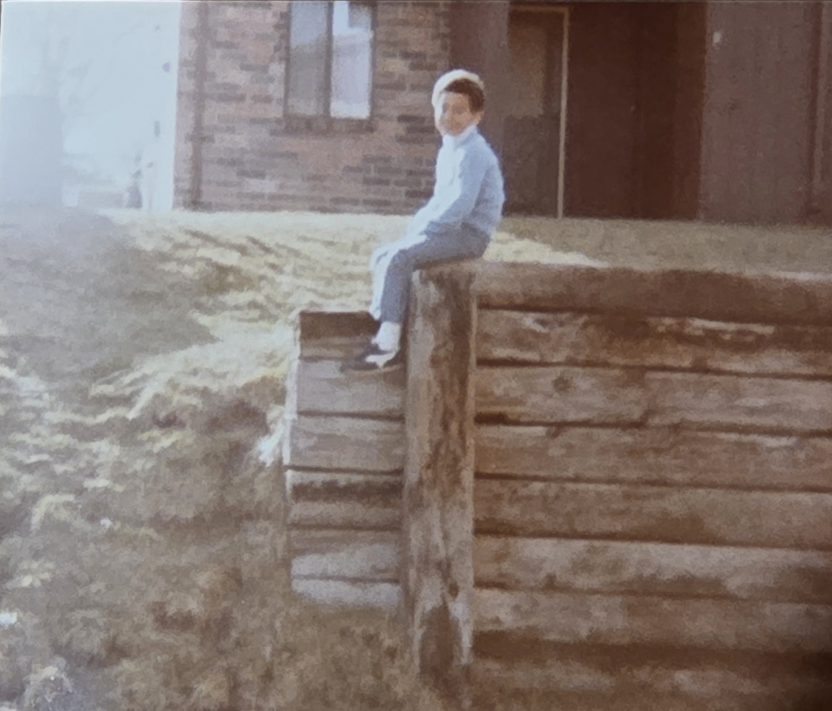 Lawyer A. Twillie II as a young child sitting on a wooden fence outside Section 8 housing